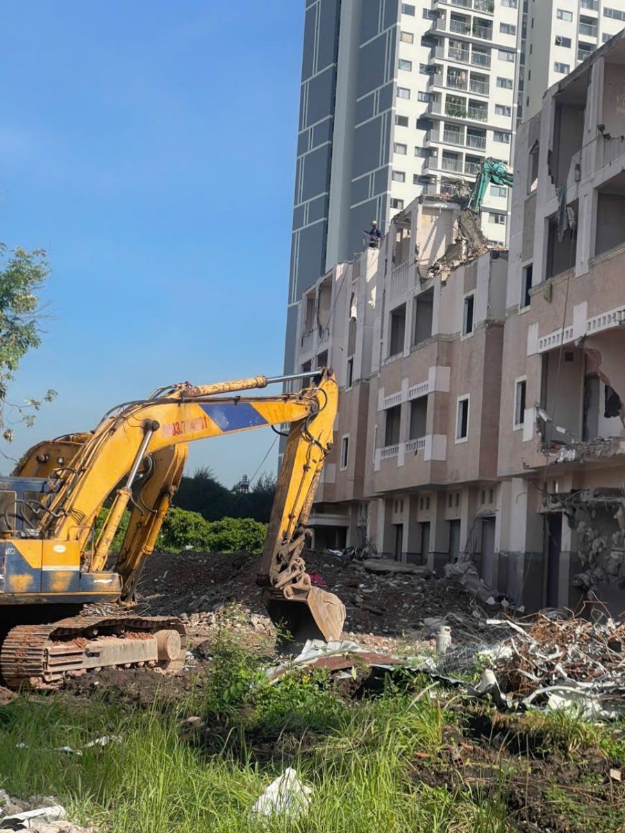 Máy đào thu gom vật liệu và xử lý mặt bằng sau quá trình phá dỡ.